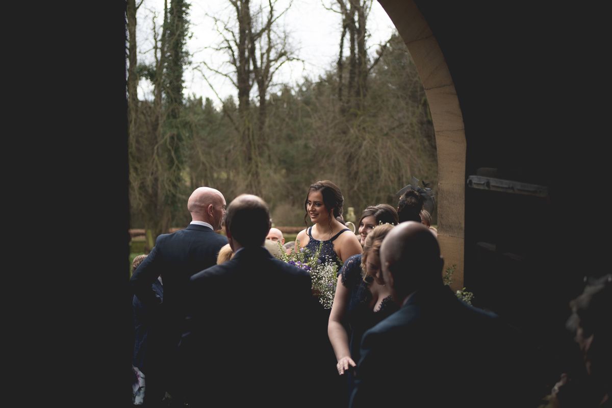 A group of wedding guests gather under an archway outdoors during a celebration.