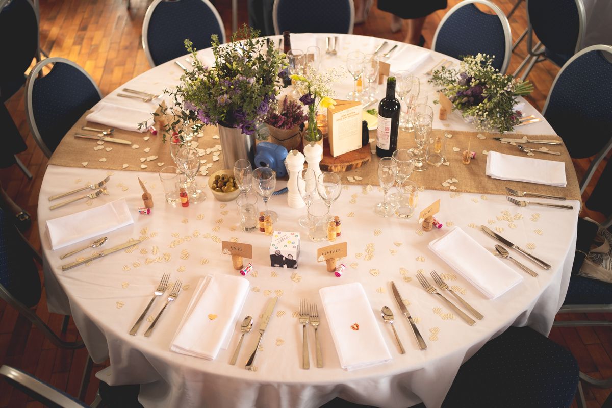 Elegant wedding reception table set with white linens and floral centerpieces.