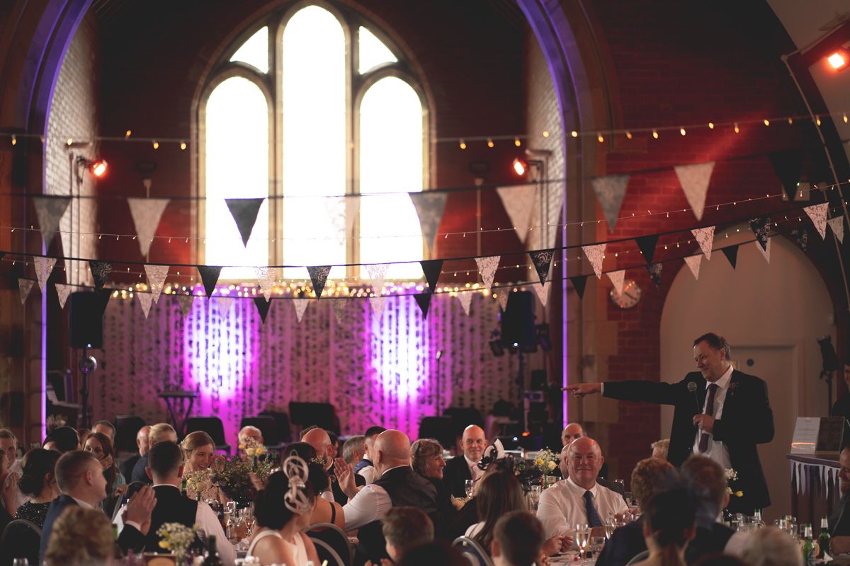 A wedding reception venue with string lights and bunting decorating a gothic-style hall.