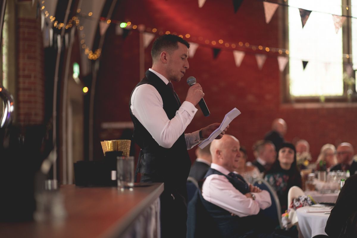 A speaker addresses wedding guests during a reception celebration.