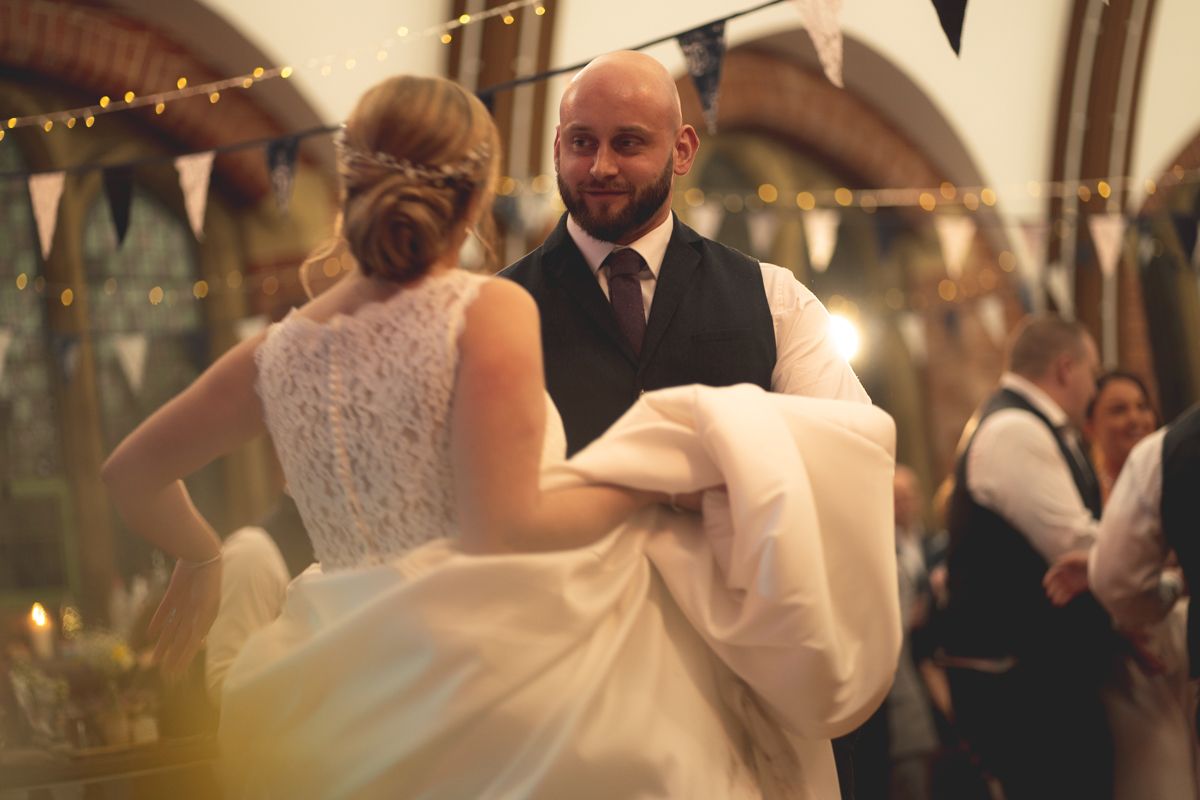 A couple dances gracefully during their reception in a beautifully lit brick venue.