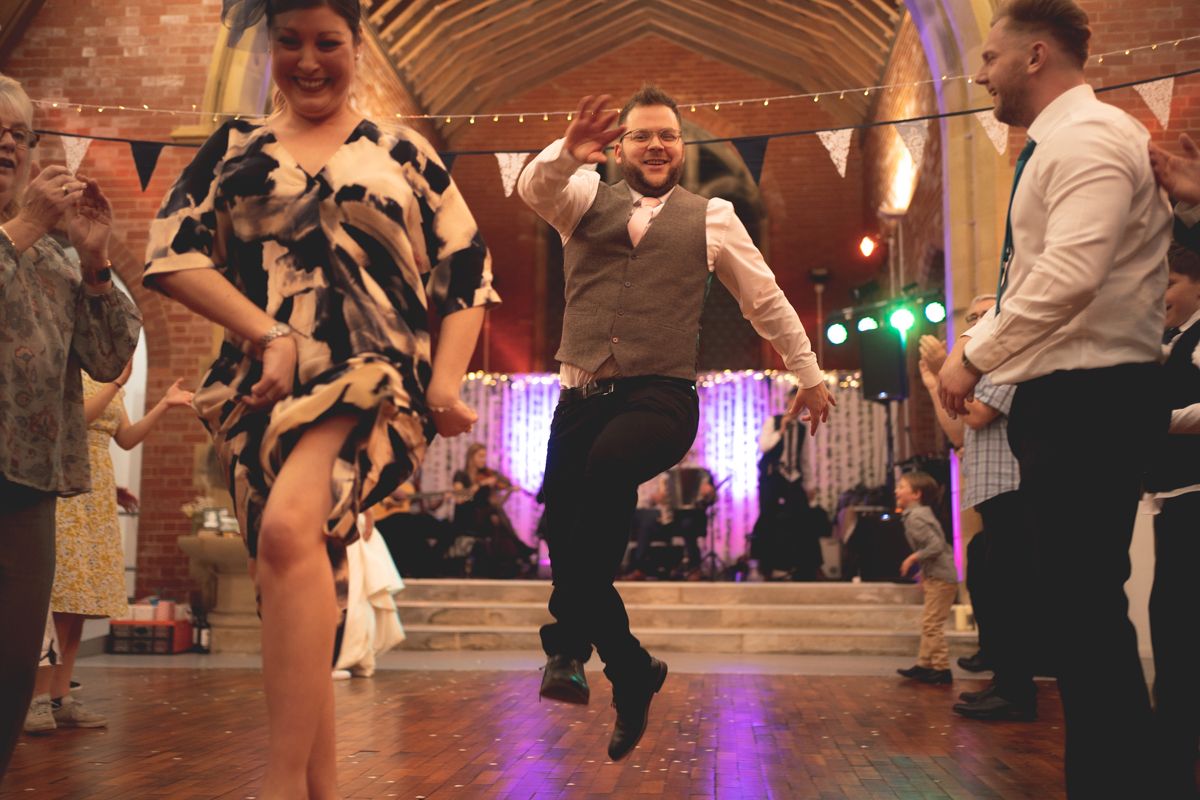 Party guests showing off enthusiastic dance moves on the reception dance floor.