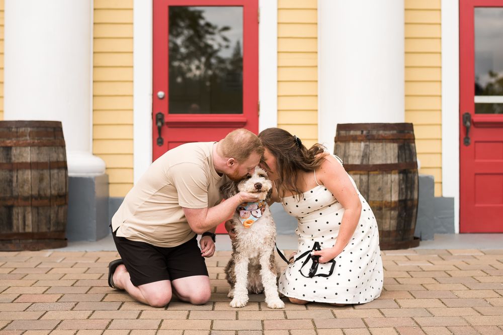 A man and woman kneel down to kiss their dog on the head in Fort Langley.