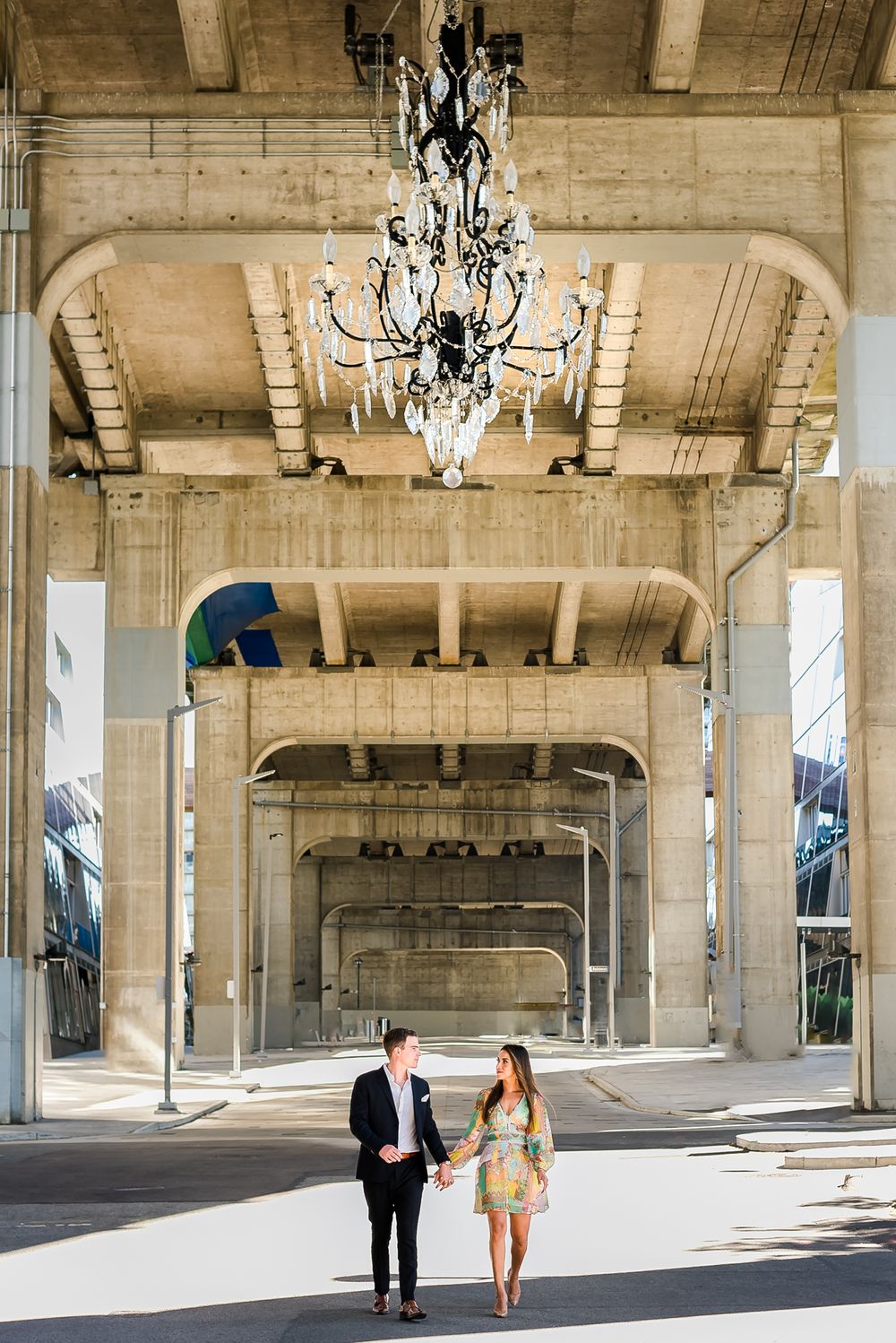 Under the Granville Street Bridge a couple go for a walk with the giant chandelier hanging above them.