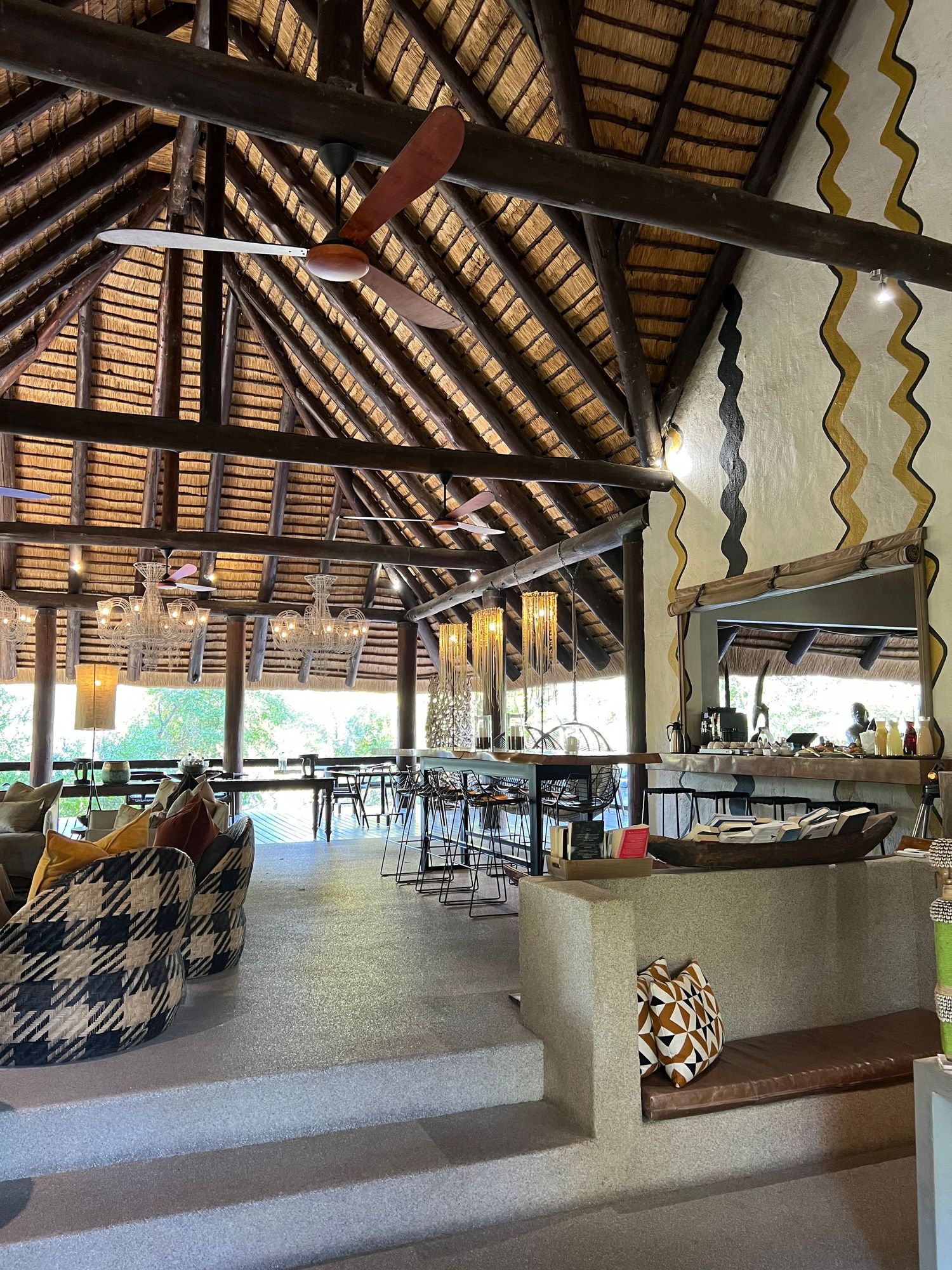 Spacious safari lodge dining area with high thatched roof and contemporary furnishings.
