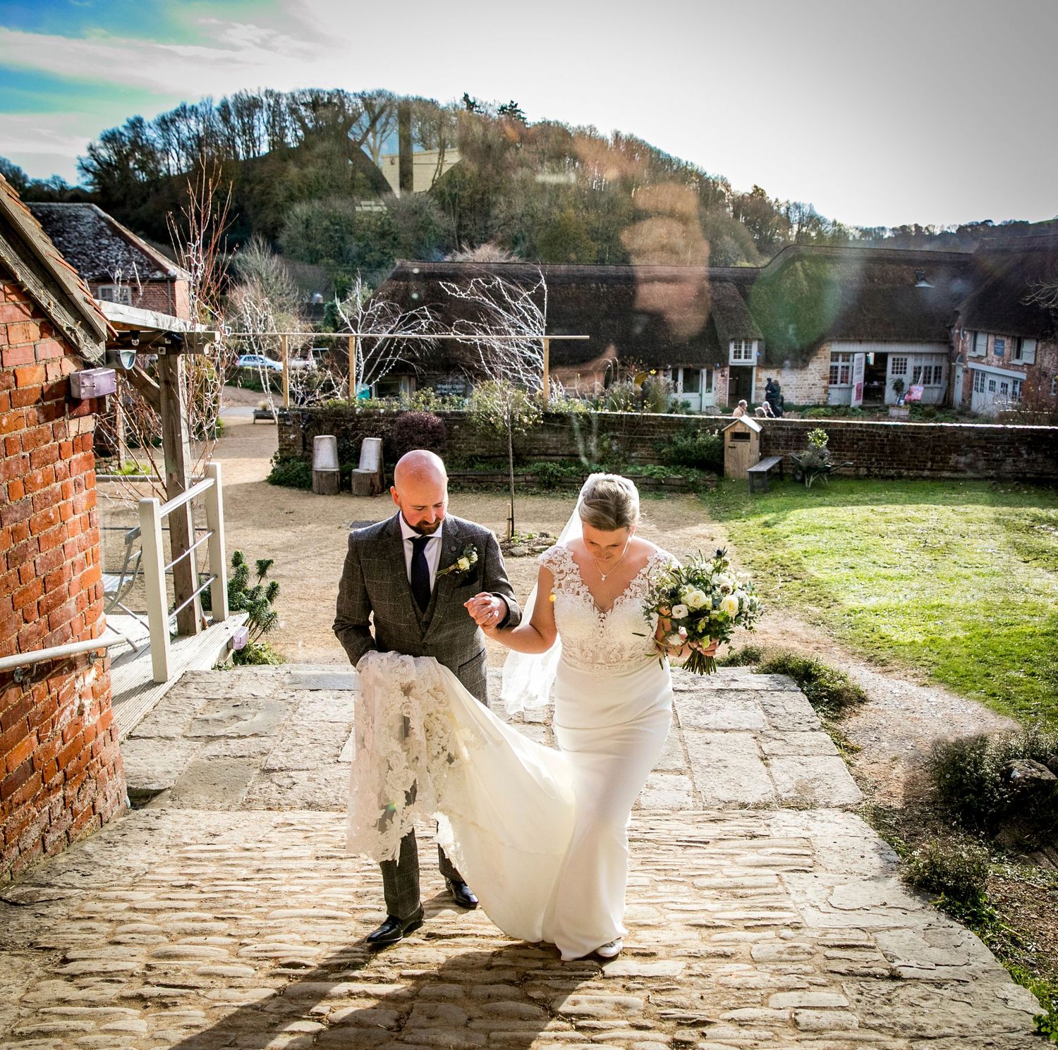 Bride and escort walking up stone steps with scenic hillside view in background.