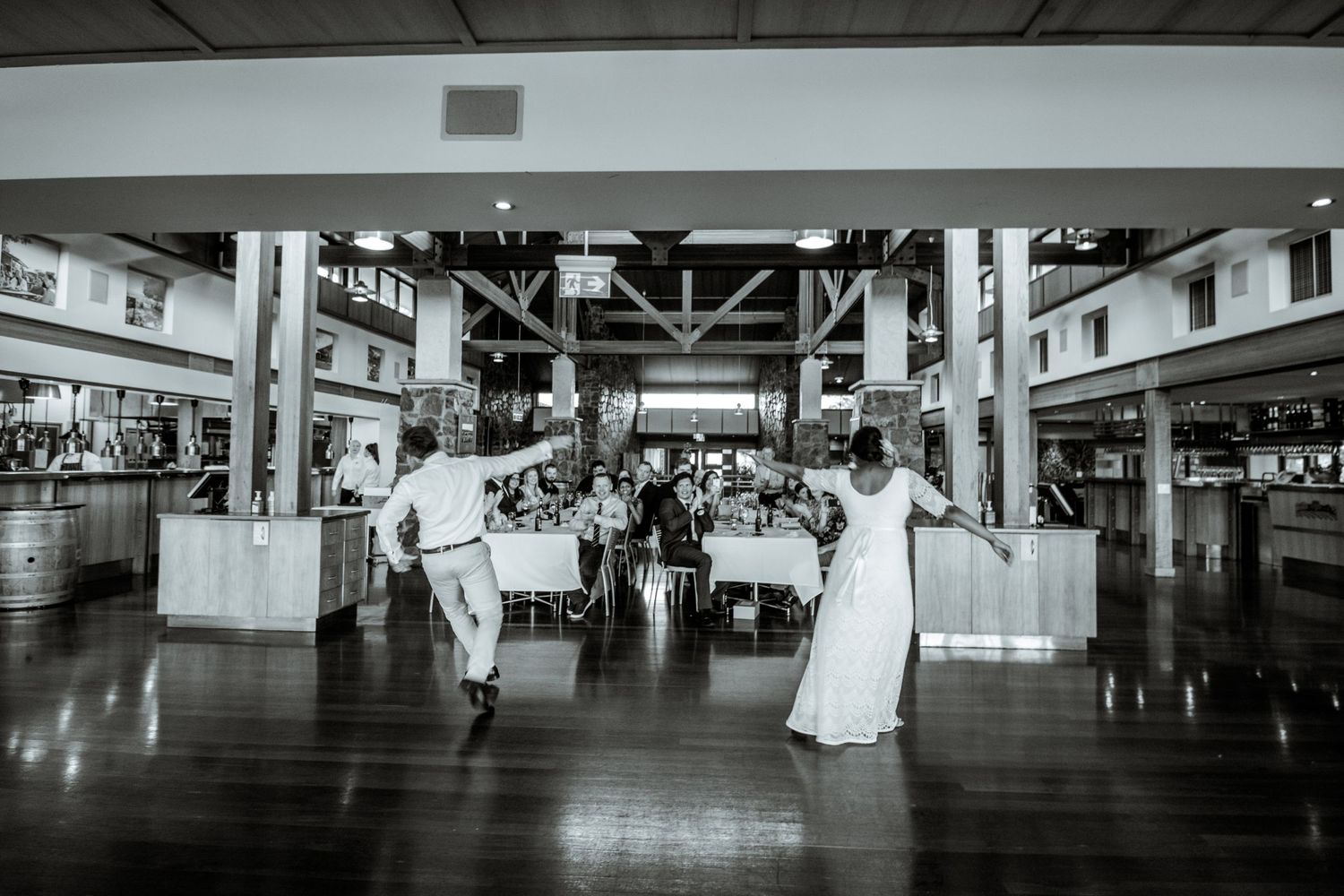 Black and white photo of reception venue with elegant table settings and architectural details.