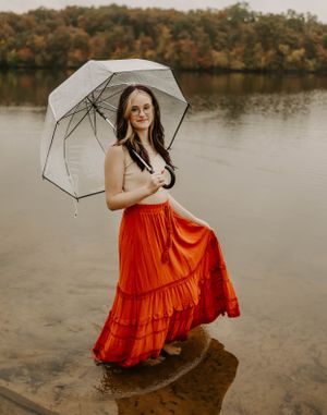 Romantic lakeside portrait with a clear umbrella and flowing red tiered skirt.
