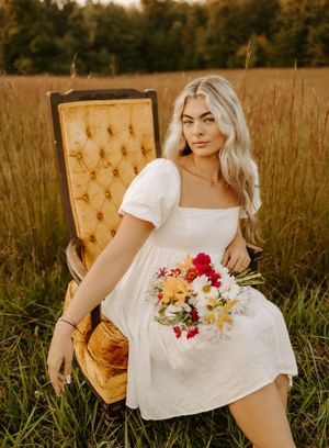 Vintage velvet chair and fresh flower bouquet create romantic scene in golden field.
