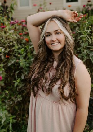 Casual portrait against floral garden backdrop with warm evening lighting.