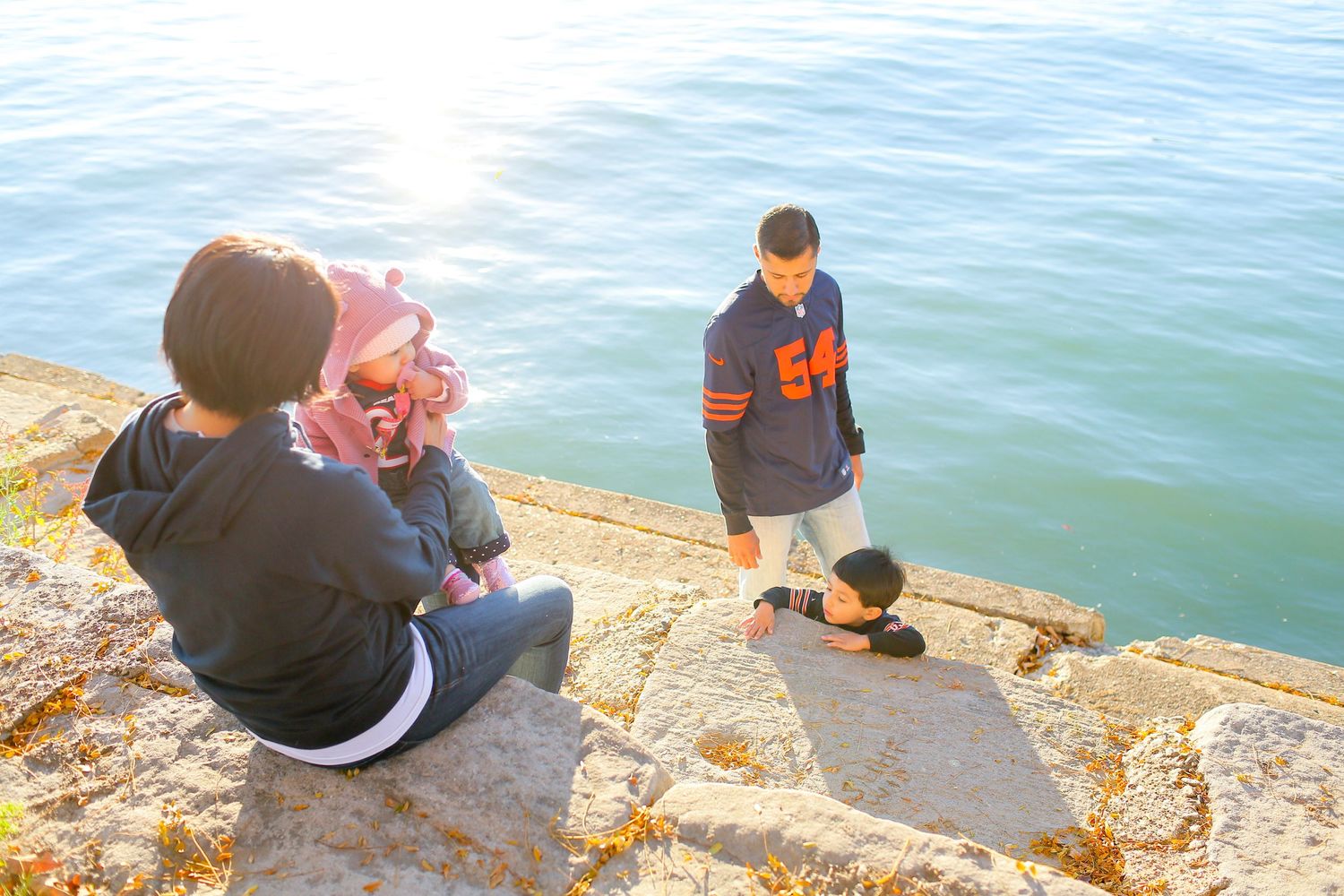 People sitting along a rocky shoreline enjoying views of blue water.
