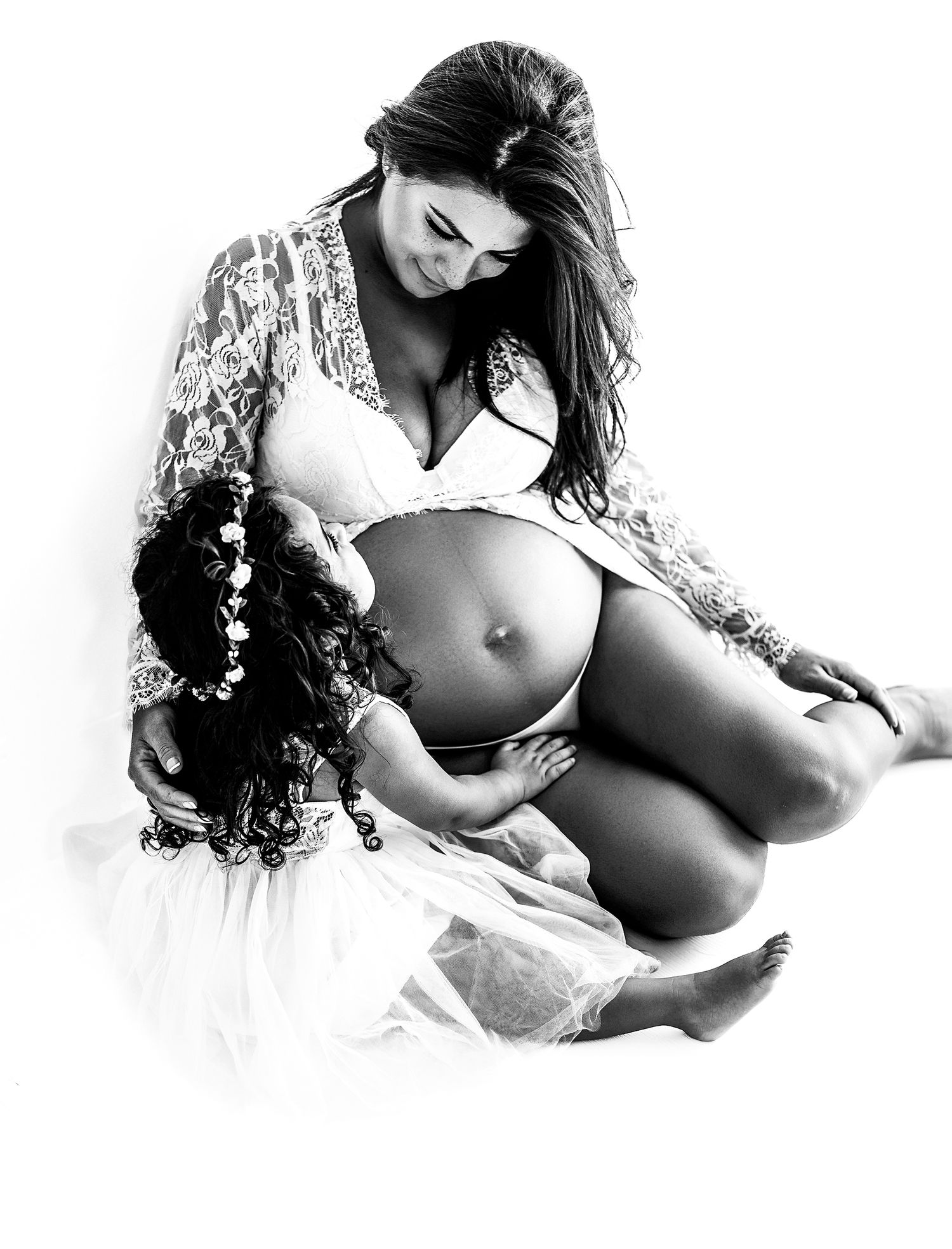 Artistic maternity portrait in black and white showing an expectant mother in lace robe.