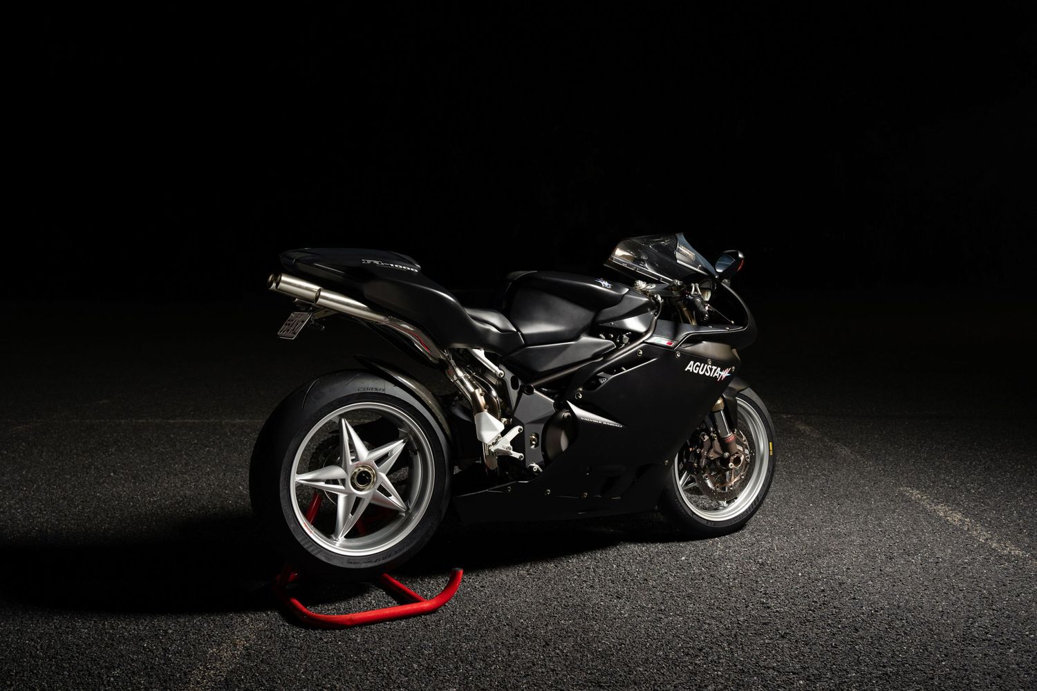 Black Ducati superbike showcased against dark background with professional studio lighting.