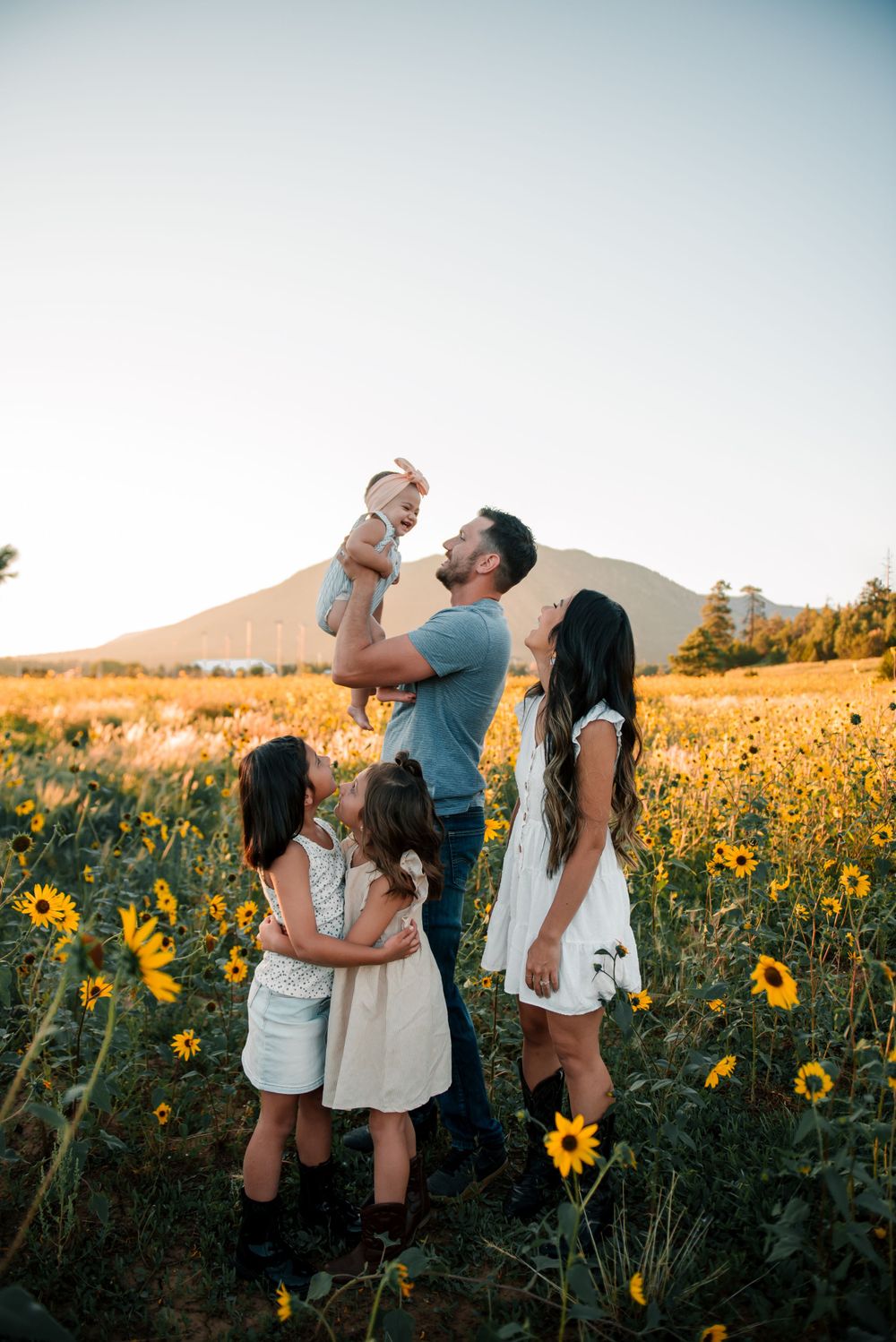 Family sharing tender moments together in a blooming sunflower field at sunset.