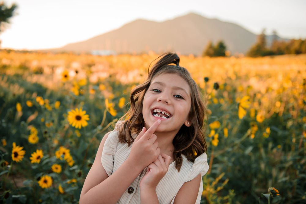A child makes silly faces while playing in a sunflower field at sunset.