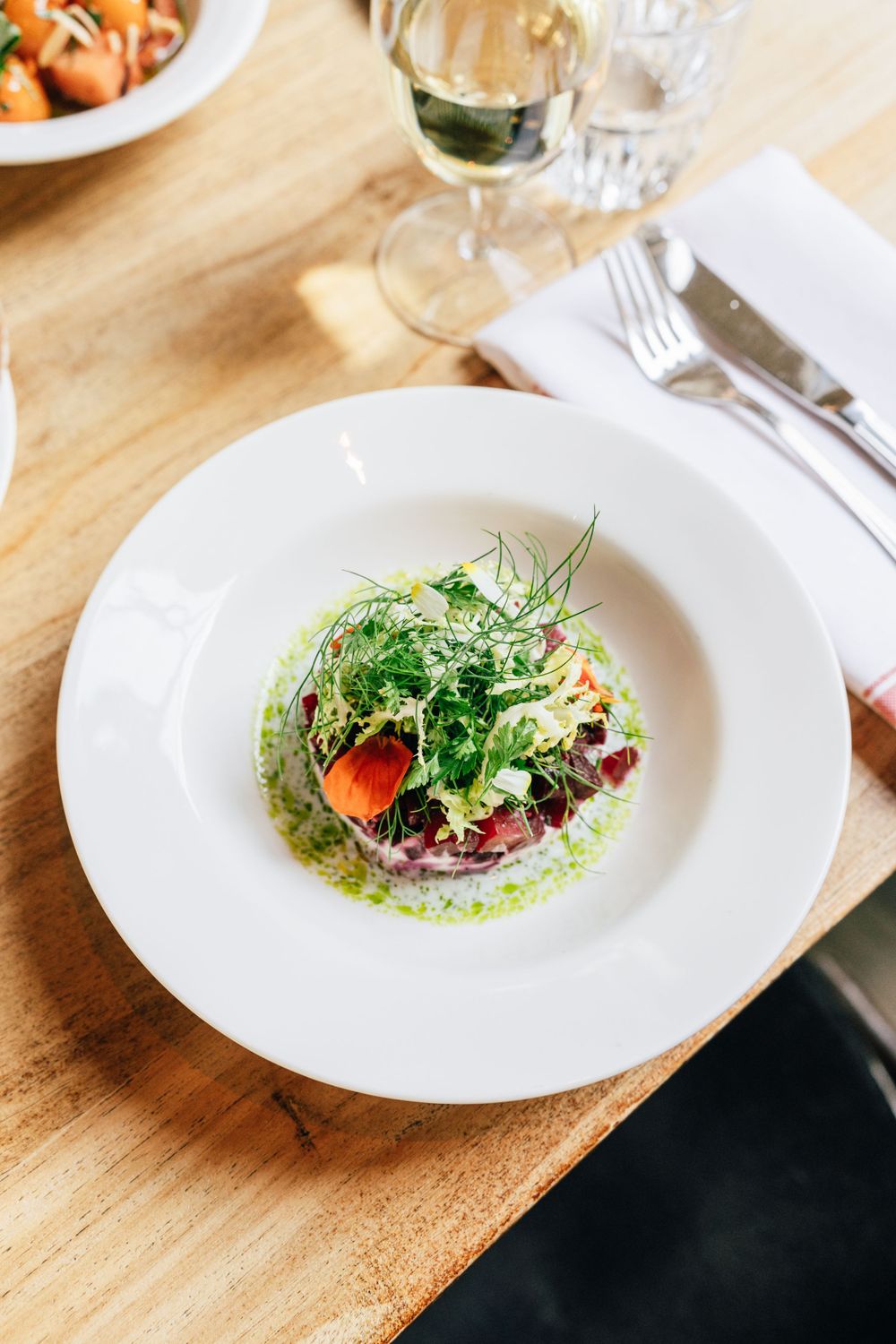 Elegant plated salad with microgreens and sauce on white dish.