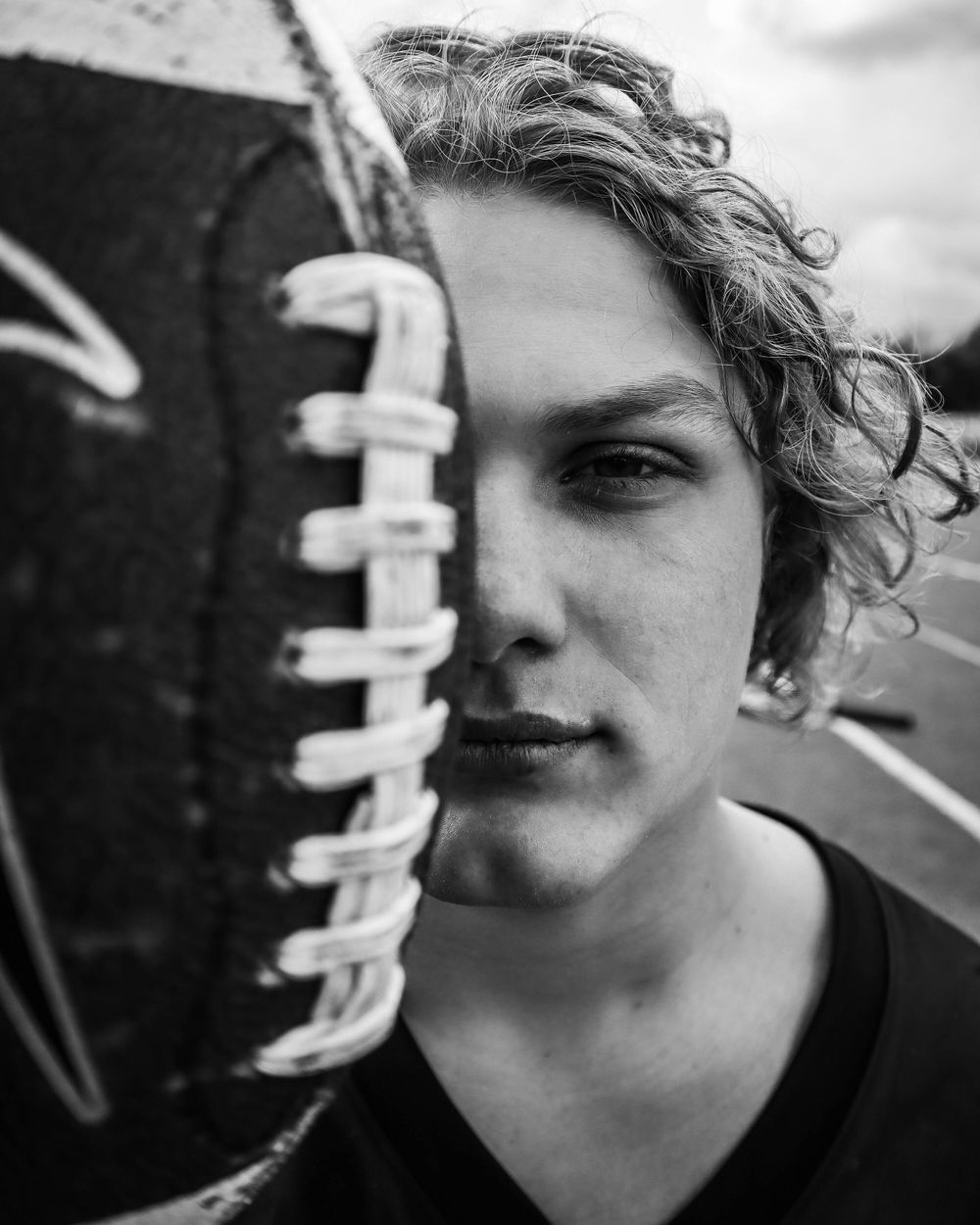 Black and white close-up portrait showing football stitching detail against a dramatic expression.