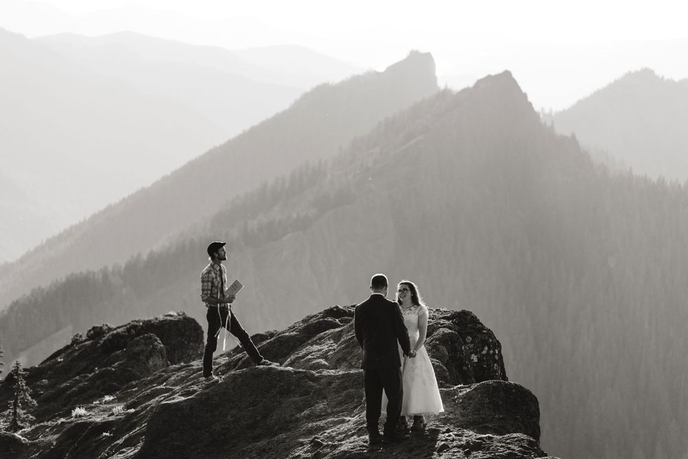 Black and white photo of an intimate mountain top elopement ceremony with officiant on rocky peak.