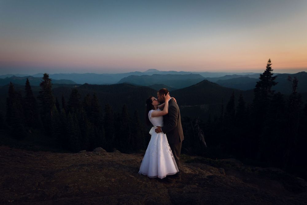 Bride and groom holding each other on a mountain overlook during a blue hour elopement.