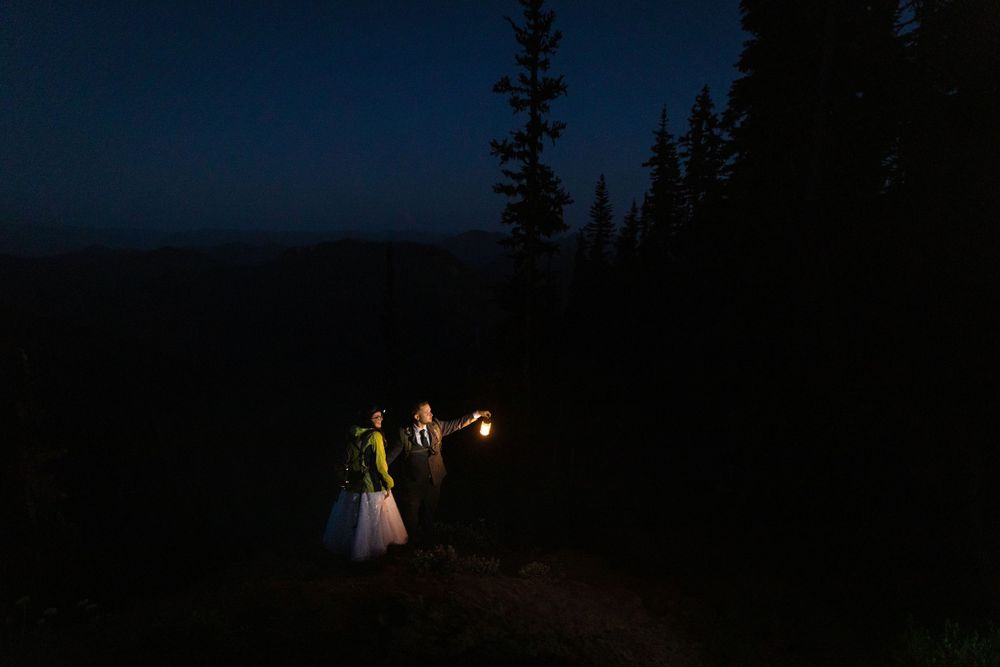 Bride and groom walking with sparklers through a dark forest at night after wedding.