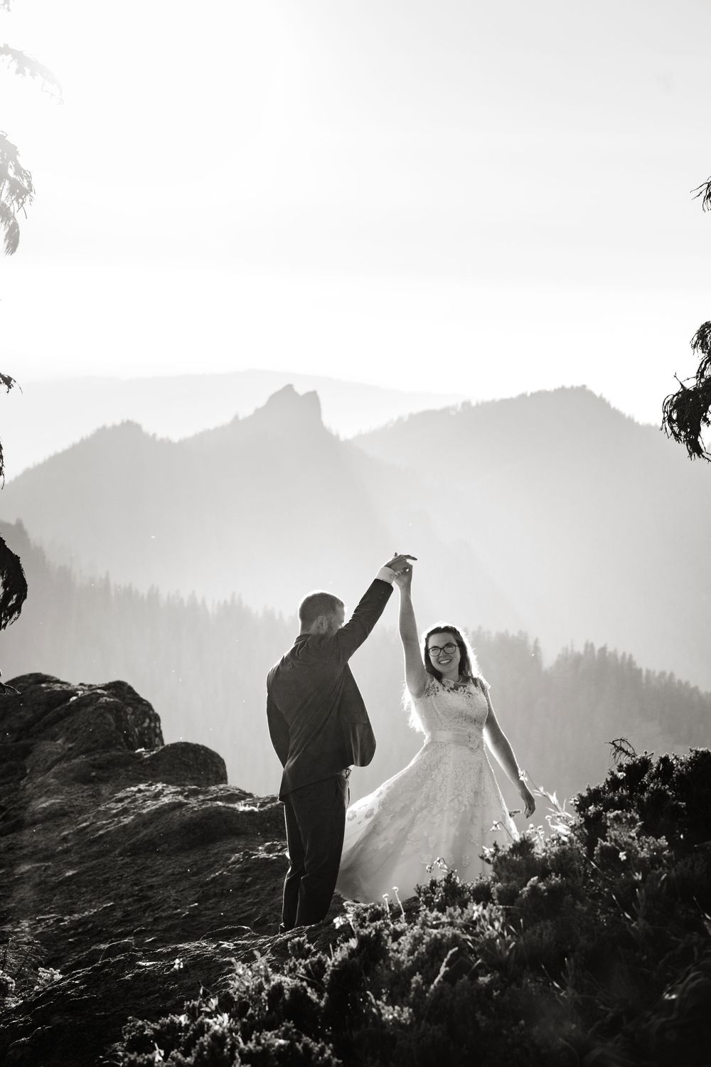 Bride and groom dancing on a rocky mountain summit in black and white wedding photography.