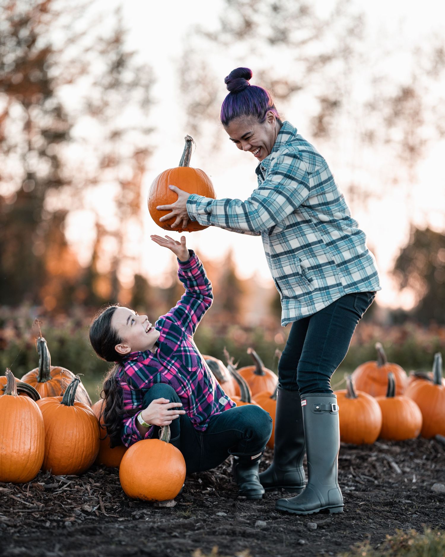 A playful autumn scene at a pumpkin patch with two people posing among orange pumpkins.