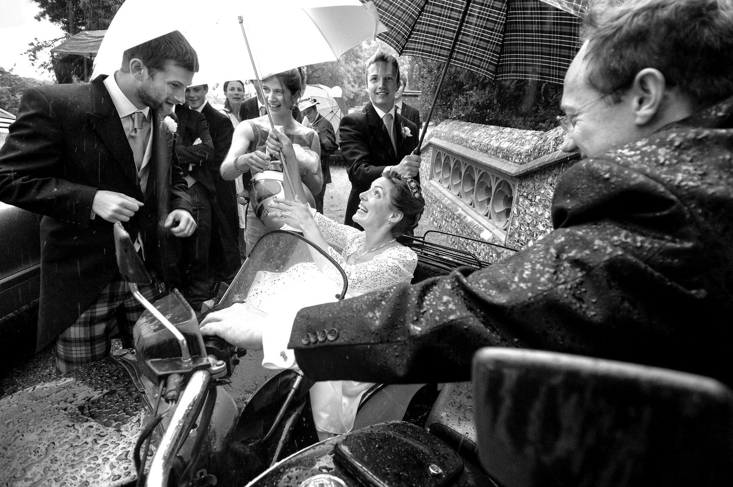 bride take cover under an umbrella as she leaves in a motorcycle sidecar