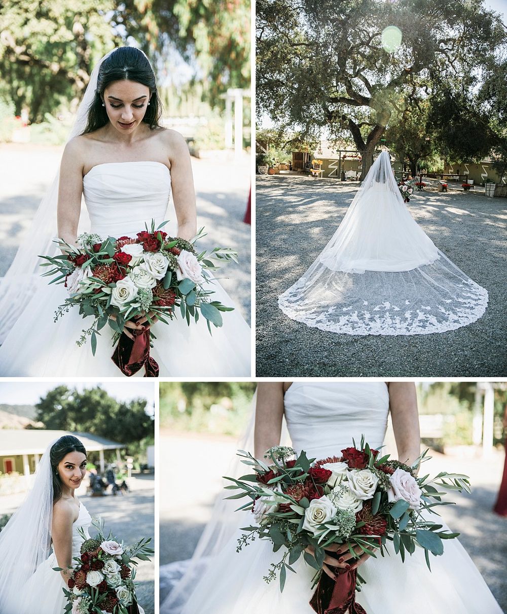 Elegant bride in a white strapless gown holds a stunning burgundy and white bouquet under a tree canopy.