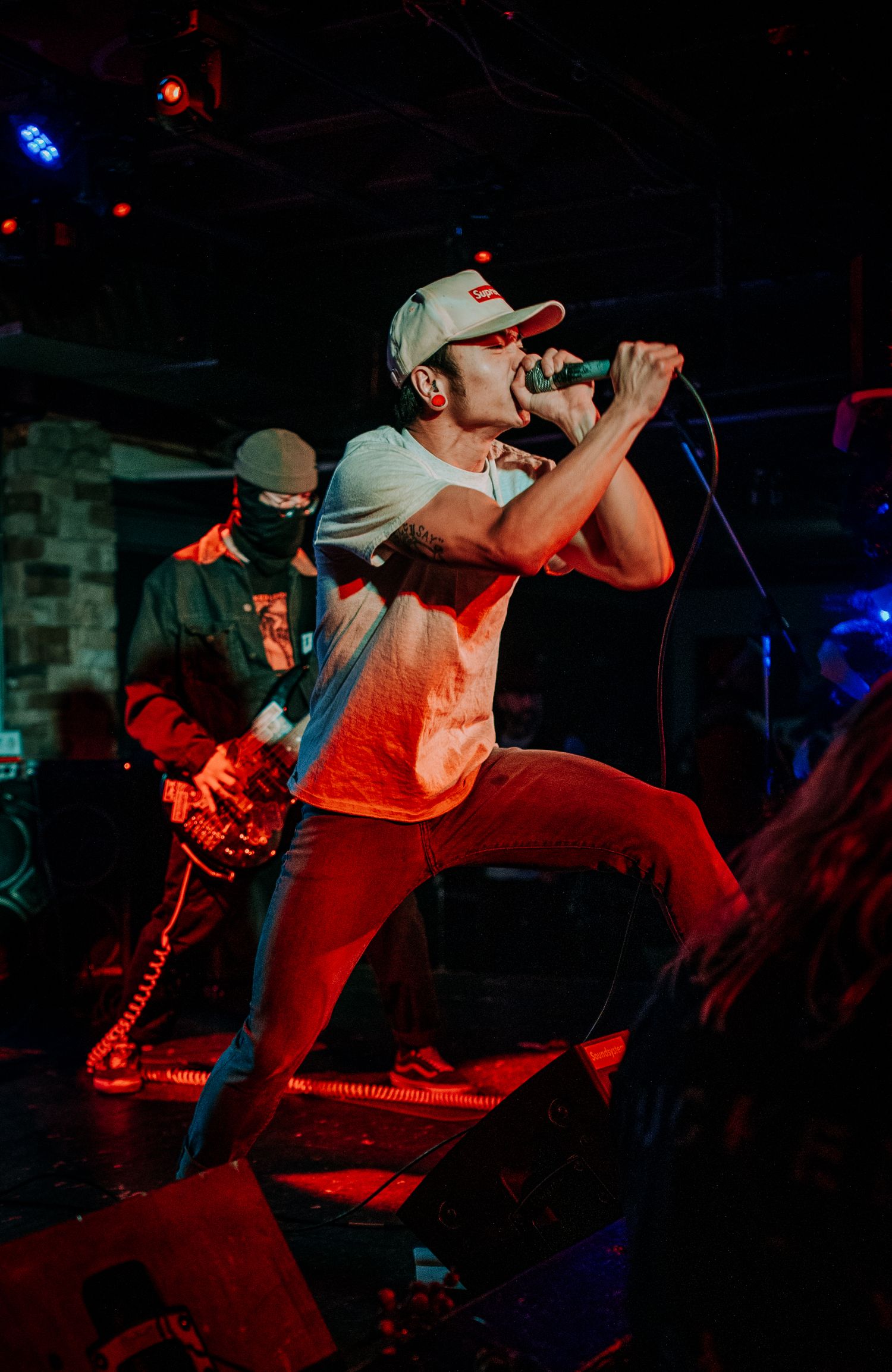 Vocalist in baseball cap performs passionately during high-energy concert.