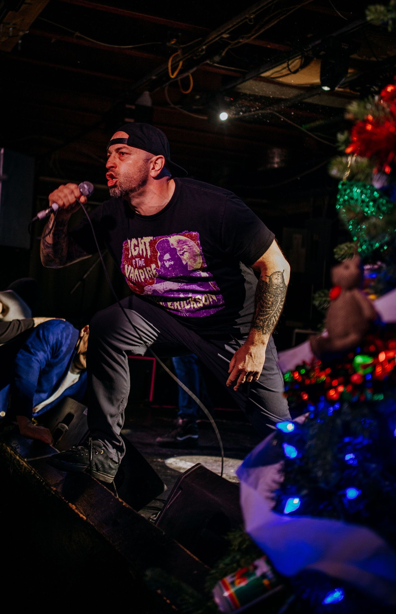 Dynamic stage performance with Christmas decorations visible and colored lighting effects.