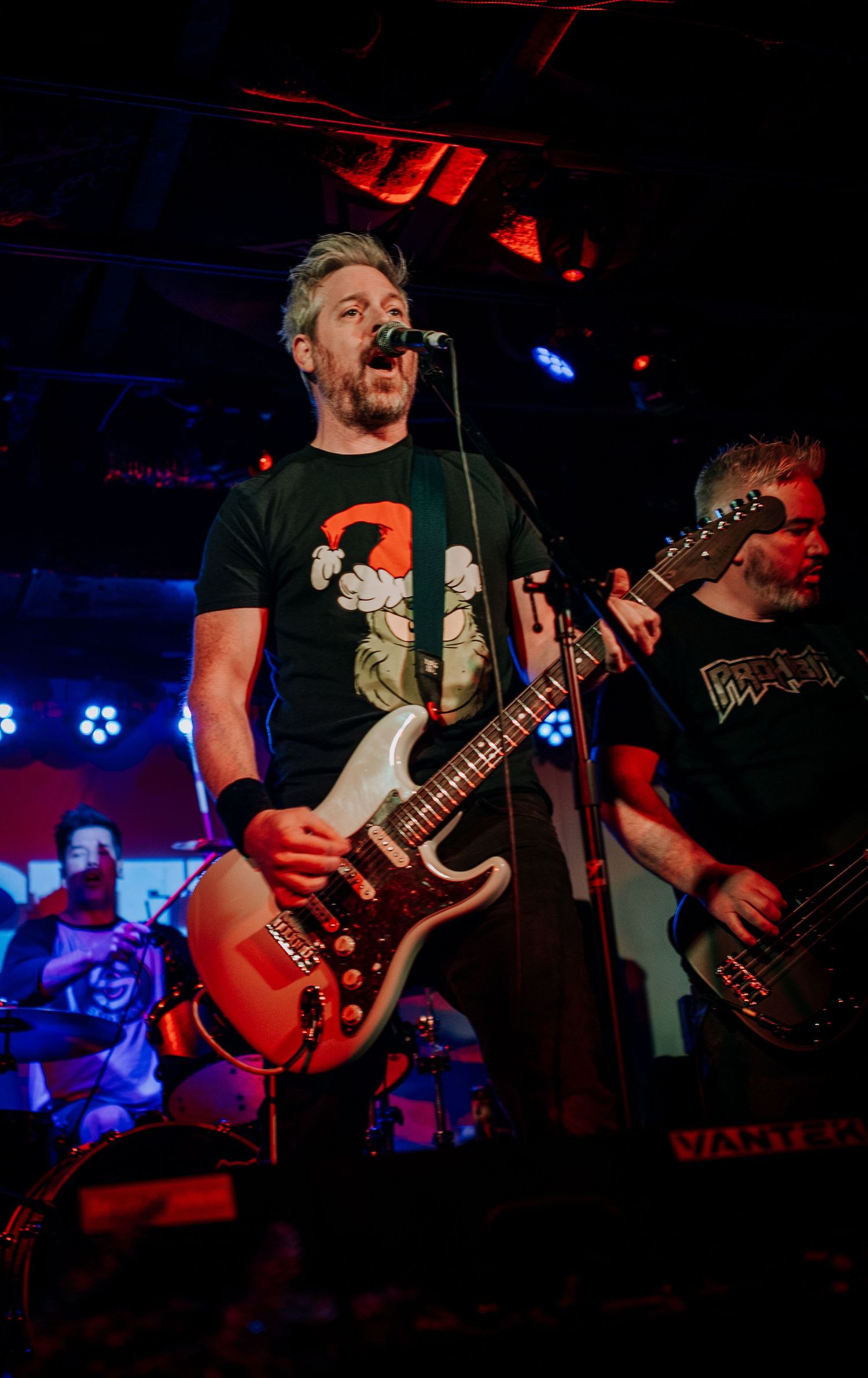 Rock musician playing red electric guitar during energetic stage performance.