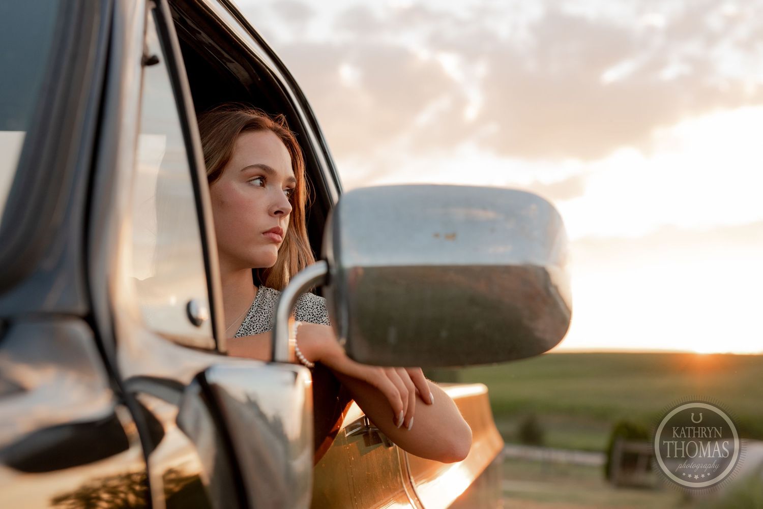 A scenic sunset view through a truck window capturing warm golden light and rural landscape.