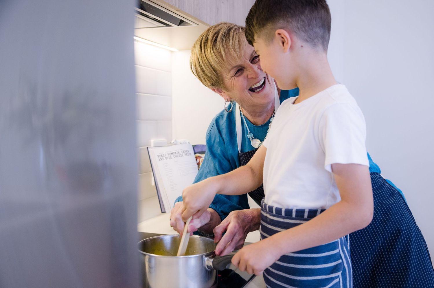 Adult and child cooking together in kitchen while sharing a happy moment.
