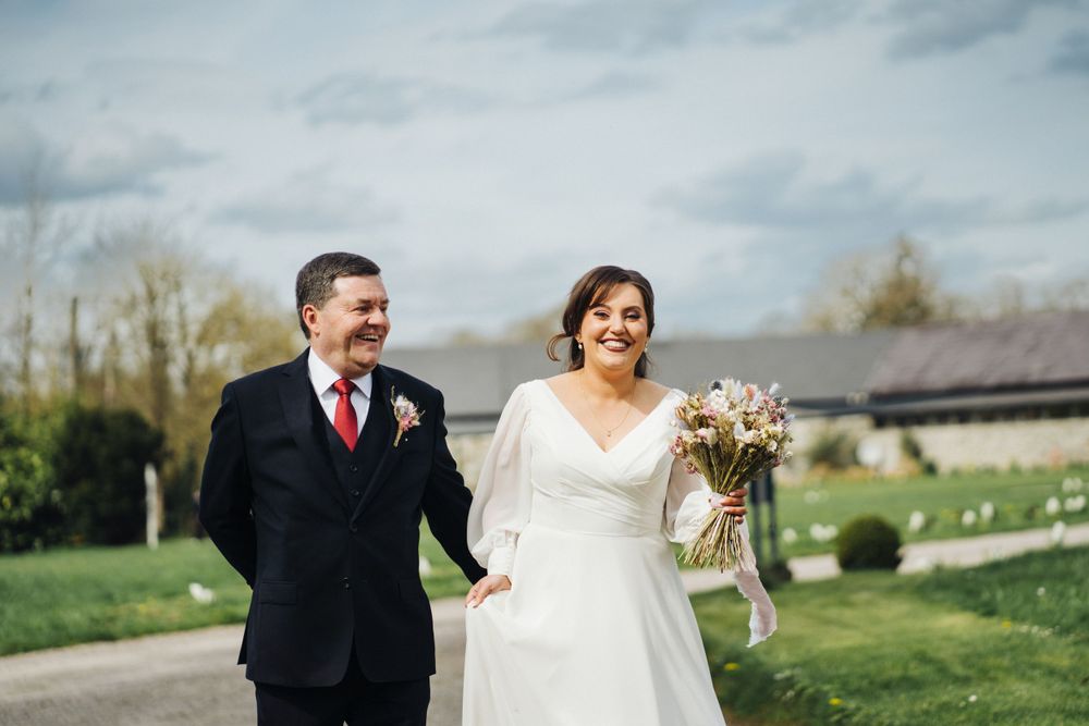 Couple walks outdoors sharing a laugh on their spring wedding day.