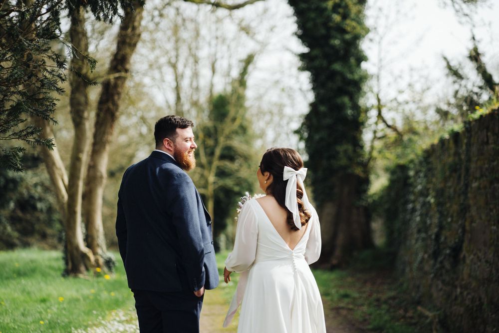 A couple shares a quiet moment together on a lush garden path during their wedding.