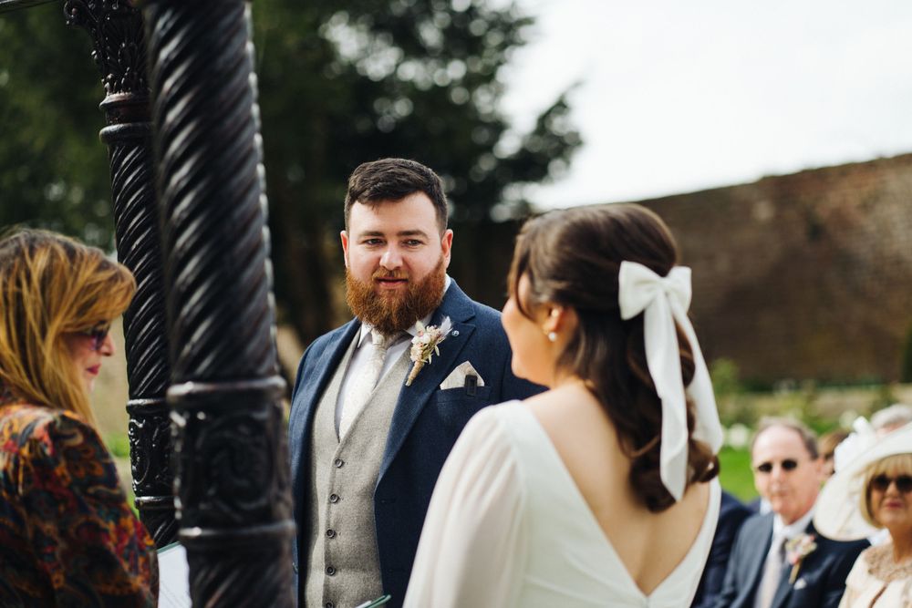 Wedding ceremony moment between couple near ornate black lamp post in garden setting.
