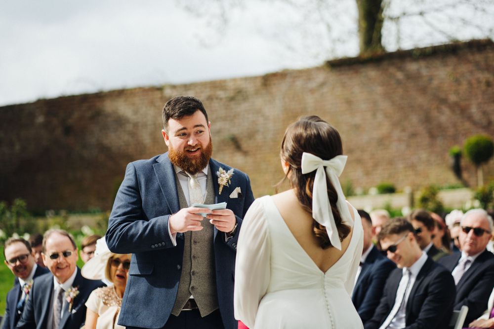 A wedding ceremony taking place outdoors with guests watching the couple exchange vows.