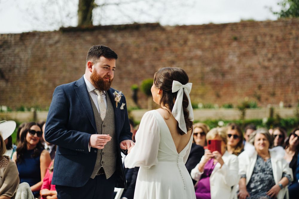 A wedding ceremony taking place on a sunny day with guests watching in background.