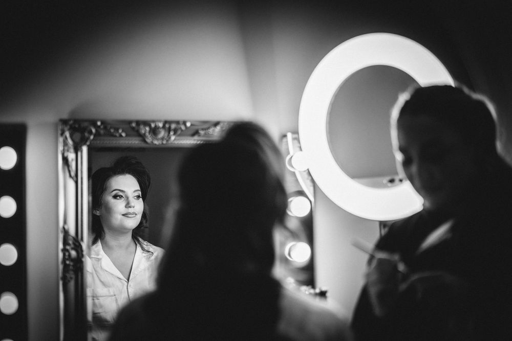 A mirror reflection in a dressing room with dramatic ring light illumination.