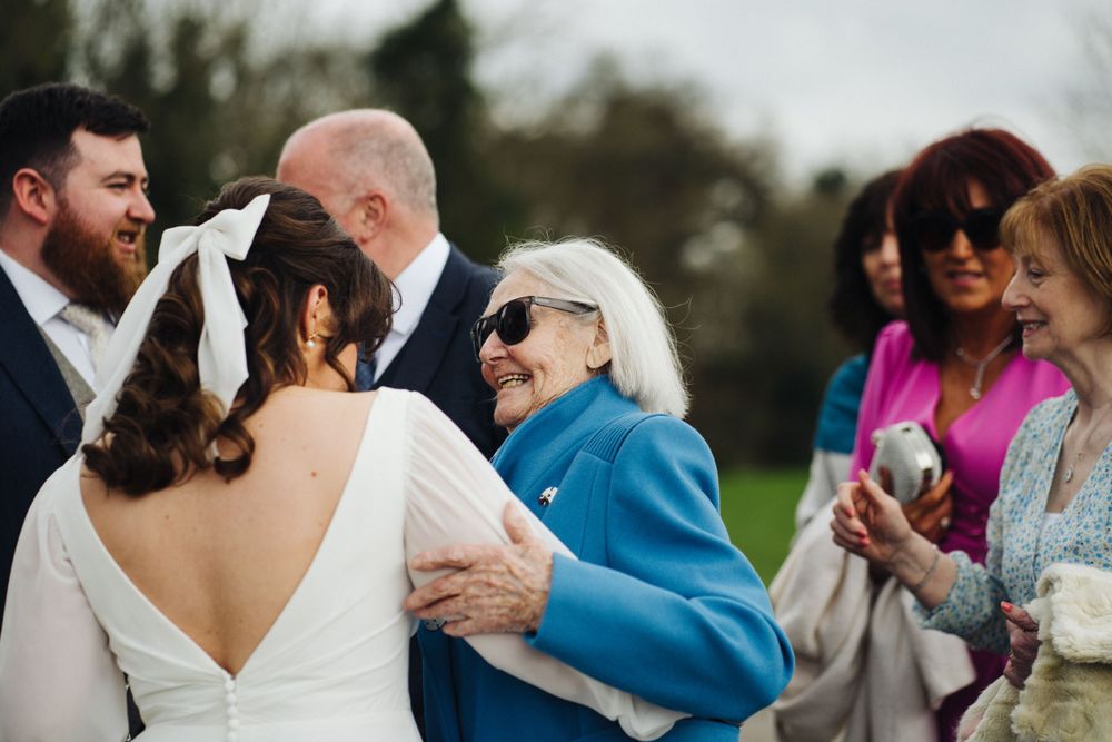 Wedding guests embrace and celebrate during an outdoor reception with warm emotions.