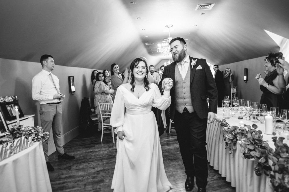 Couple makes their grand entrance at wedding reception in elegant venue with draped ceiling.