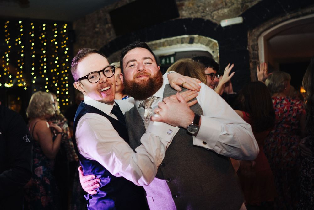 Friends embrace and celebrate during lively wedding reception party.
