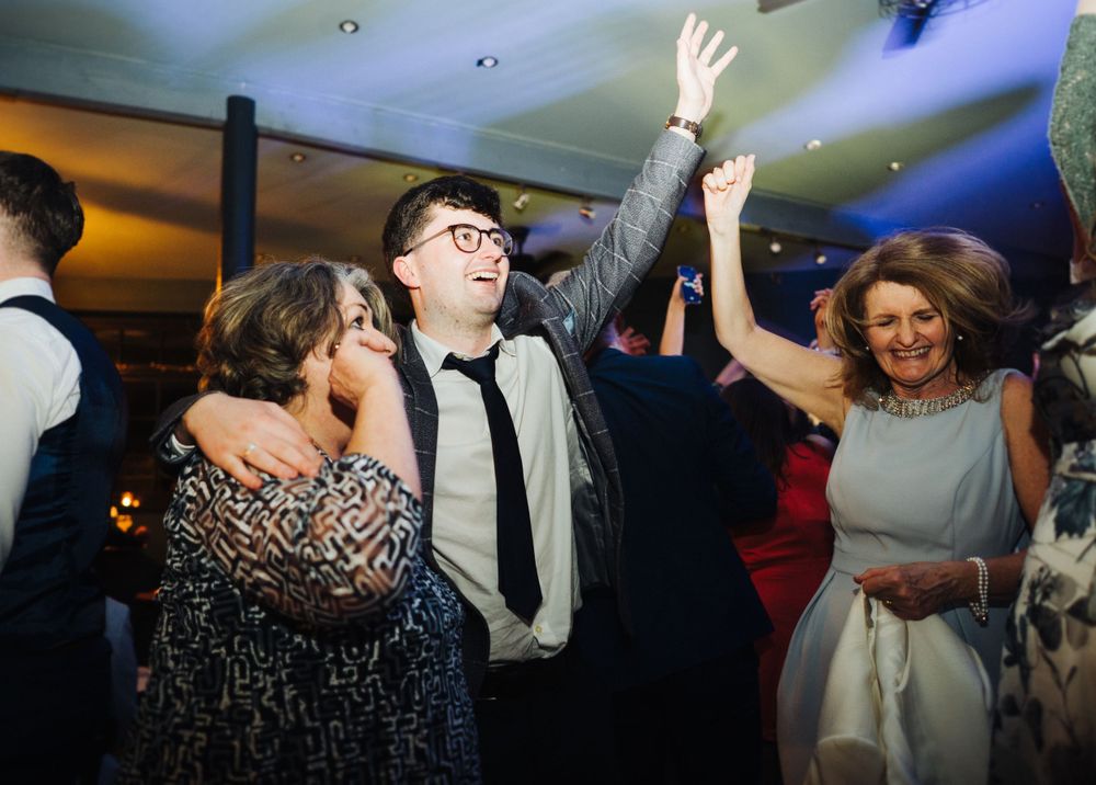 Wedding guests dancing enthusiastically during reception celebration.