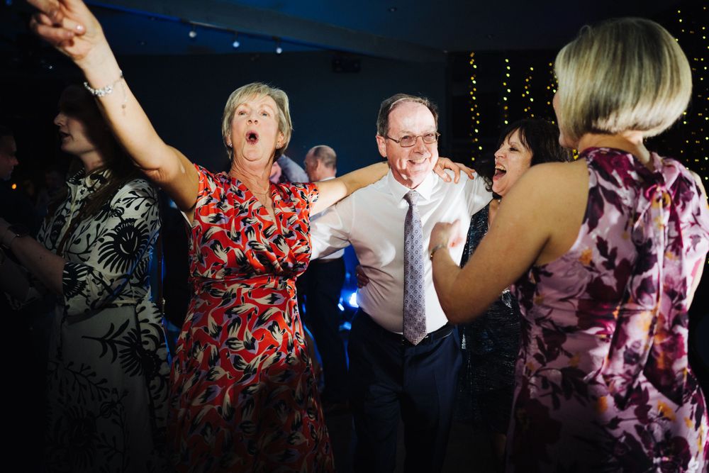 Wedding guests dancing joyfully at evening reception party.