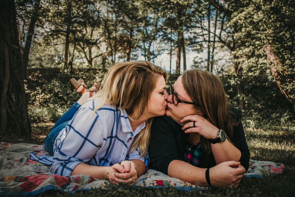 Two young women steal a kiss on a picnic blanket