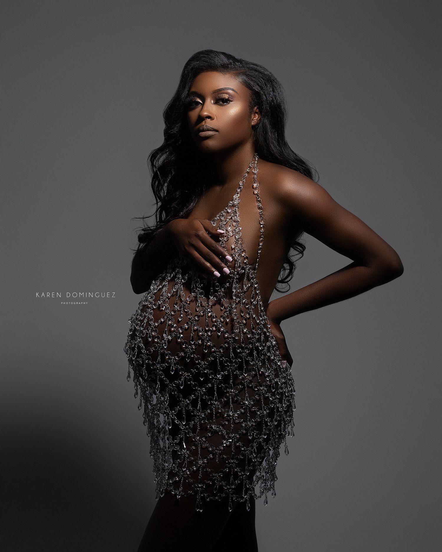 A dramatic black and white fashion portrait showcasing a sparkling sequined dress against a dark background.