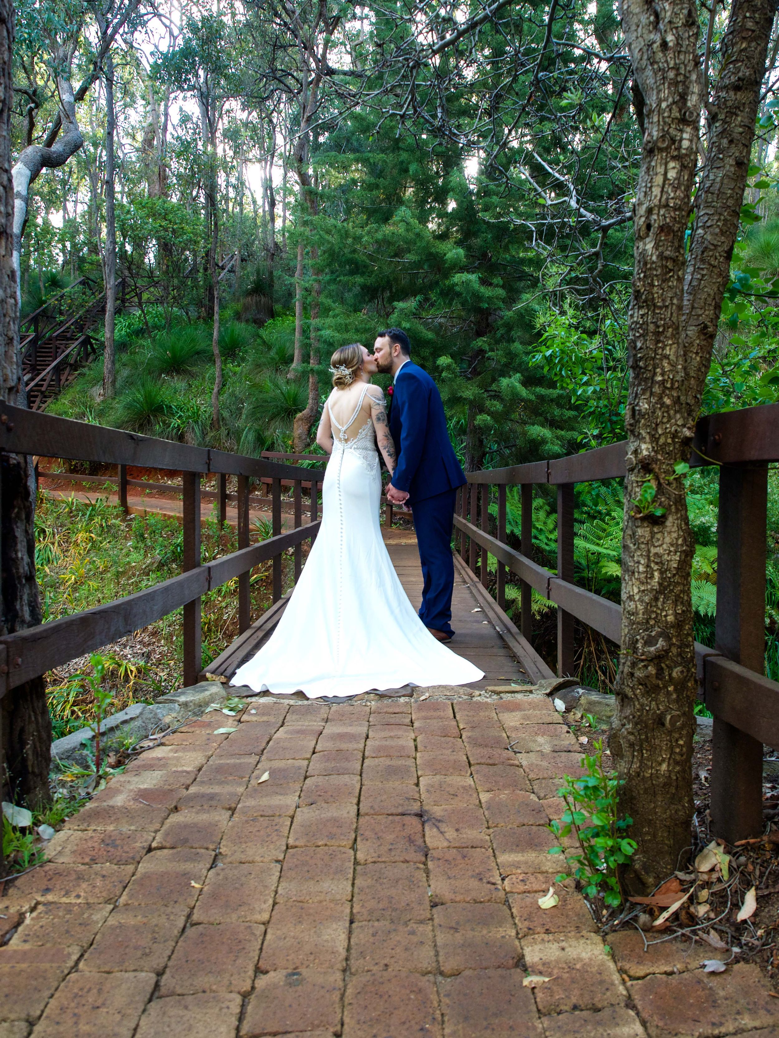 Spring outdoor wedding at stunning Araluen Botanical garden with the bride  wearing a wedding dress and groom in blue