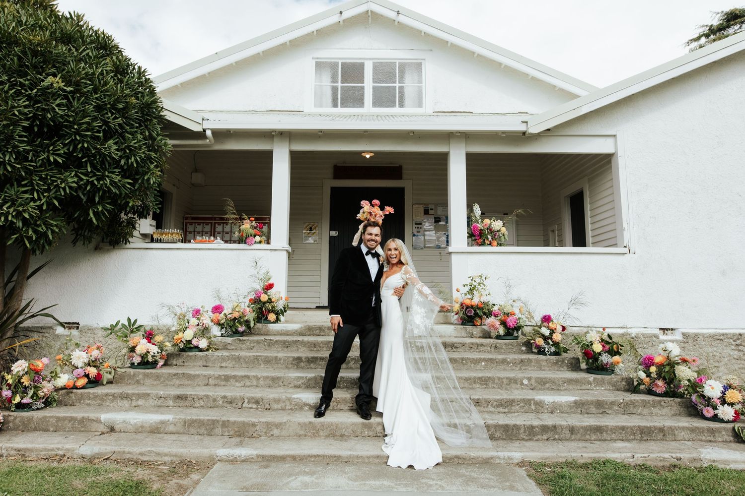 Classic white house wedding venue with steps decorated in pink and peach floral arrangements.