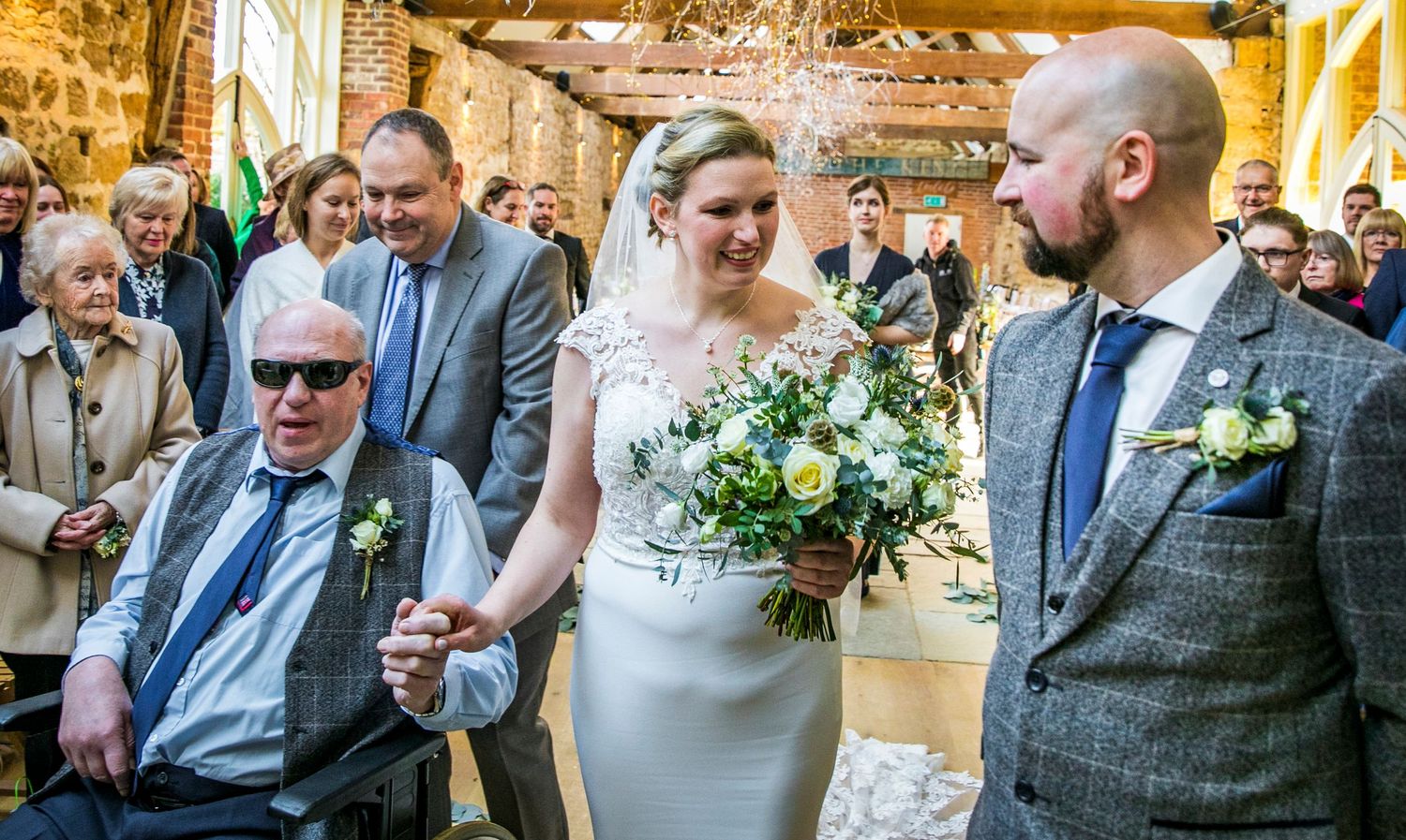 Wedding ceremony in a rustic venue with elegant chandelier and floral decorations.