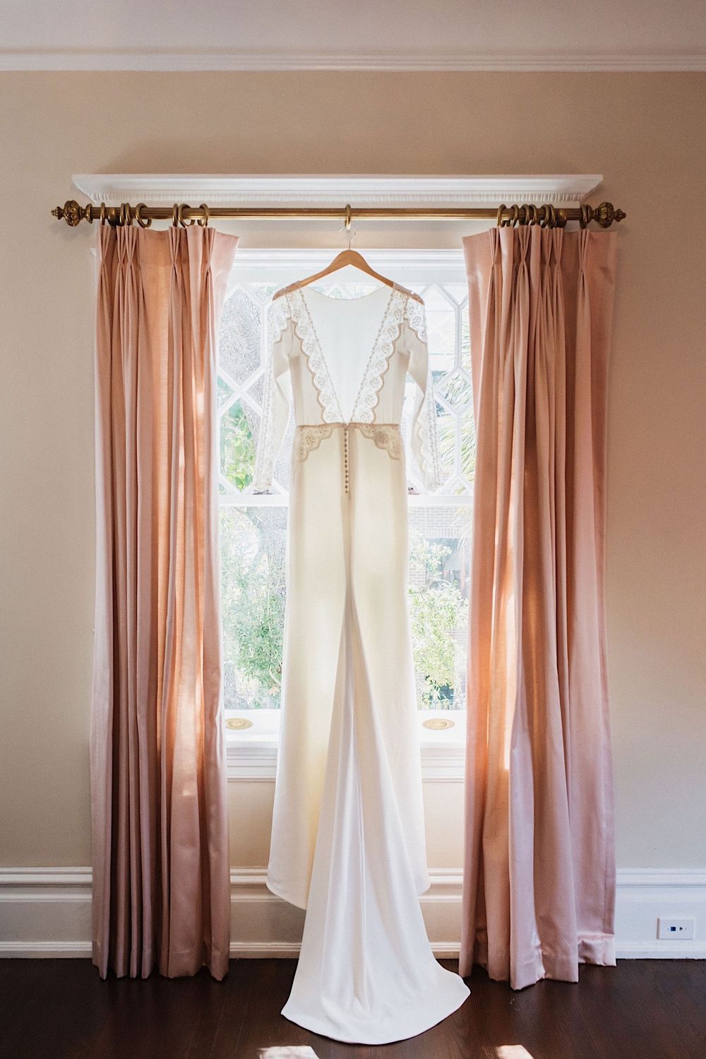 Wedding dress hanging in the window with pink curtains at the Orlo , a wedding venue in Tampa, FLorida